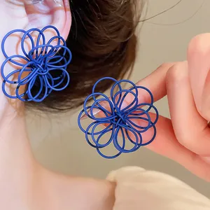 Detailed close-up shot of blue painted wire flower earrings with unique tangled lines design.