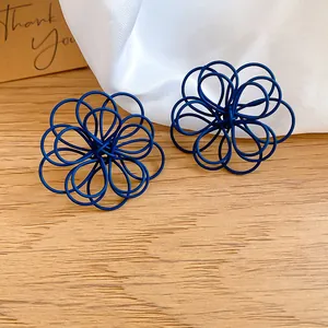 Detail of blue spray-painted wire-wrapped flower stud earrings on wood surface