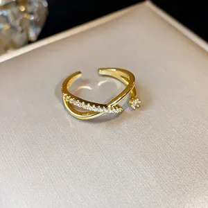 Dettaglio anello incrociato placcato oro 14k con zirconi luminosi e fascia regolabile