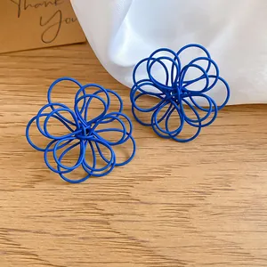 Macro detail view of blue matte spray-painted coiled wire flower stud earrings
