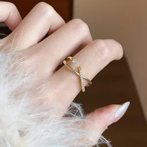 Dettaglio di un anello incrociato placcato oro 14k con un piccolo zircone a forma di stella.