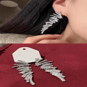 Vue détaillée des boucles d'oreilles pompons géométriques avec pierres zircon