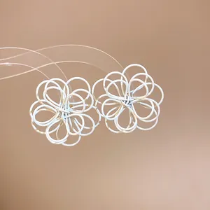 Close-up of elegant white spray-painted wire-wound flower earrings on beige background