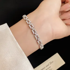 Macro view of a 14k gold-plated zircon interlocking link bracelet worn on a slim wrist