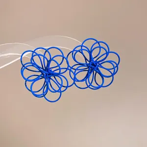 Close-up of blue spray-painted wire-wrapped flower earrings with unique design.