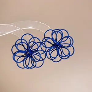 Close-up view of matte blue wire-wrapped floral stud earrings with minimalist artistic design