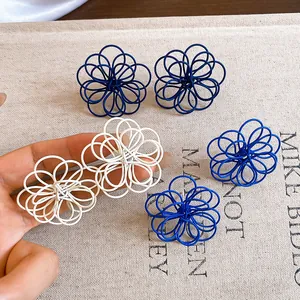 Close-up detail of three-dimensional wire wrapped flower stud earrings in white and blue