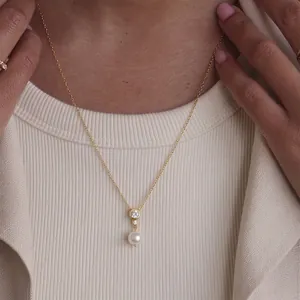 Elegante 18k vergulde ketting met hanger van zirkoon en parel op model, bruidsjuwelen