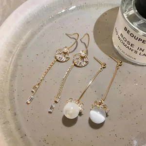 Close-up view of elegant gold-toned long tassel earrings featuring shell and pearl details