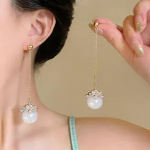 Detail of long tassel earrings with dainty floral design and white pearl drops.