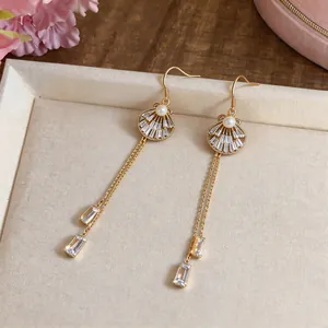 Elegant long gold tassel earrings with shell design, white crystals and pearls