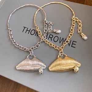 Close-up detail of silver and gold textured lip pendant necklaces with crystal accents