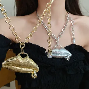 Close-up of textured gold and silver metal lip pendants on chunky link chains