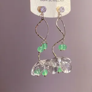 Boucles d'oreilles pendantes en résine avec spirale argentée et perles vertes.