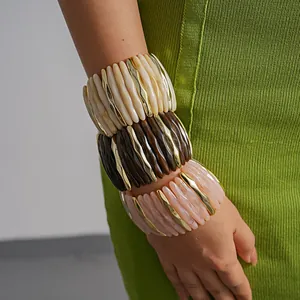 Detail shot of layered chunky marbled acrylic and gold-toned metallic elastic bracelets.
