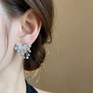 Silver needle zircon butterfly stud earrings worn on ear with dainty pearl drop details