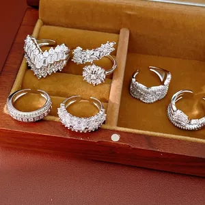 Elegant silver-toned zirconia V-shaped and flower rings set in a wooden jewelry box