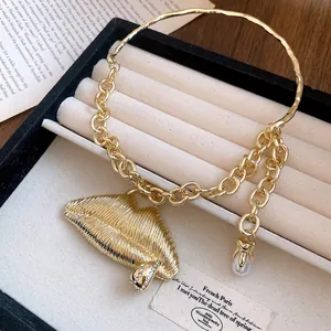 Detail of a gold-toned necklace featuring a textured lips pendant with rhinestones and a pearl