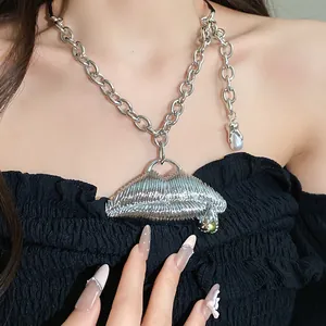 Close-up of a chunky silver chain necklace with a textured metallic lip pendant