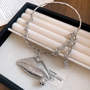 Macro view of textured silver lip pendant with diamond accents on a chain