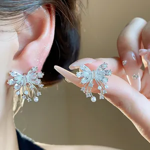 Close-up of elegant butterfly stud earrings with sparkling cubic zirconia and pearls.