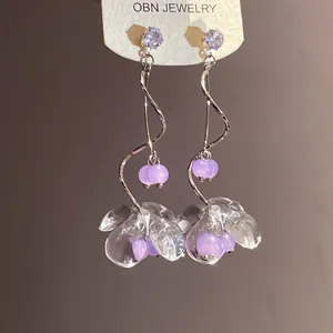 Vue détaillée d'élégantes boucles d'oreilles en résine avec perles violettes et spirales