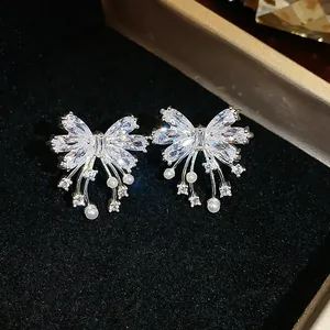 Elegant close-up of bow-knot stud earrings featuring sparkling zircons and white pearls