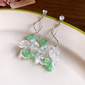 Boucles d'oreilles élégantes en résine fleur de muguet avec perles vertes et crochets.