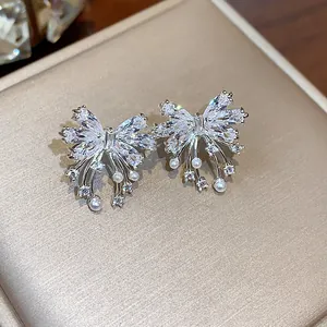 Detailed view of silver bow stud earrings with sparkling zircons and delicate pearls