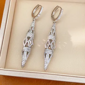 Detailed view of luxury silver hollow rhombus drop earrings with pavé sparkling stones.