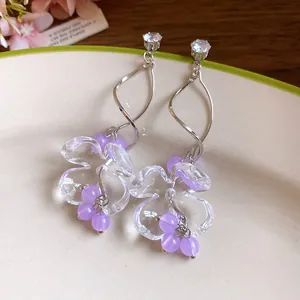 Détail de boucles d'oreilles style français avec fleurs en résine et perles violettes