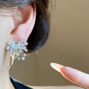 Macro shot of a sparkling silver butterfly stud earring with zircon and pearl details.