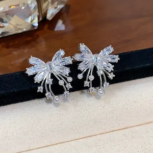 Macro detail showing shimmering zircon butterfly stud earrings with delicate pearl accents
