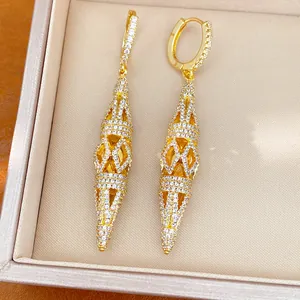 Close-up of elegant gold-toned dangling earrings with hollow rhombus design and clear crystals.