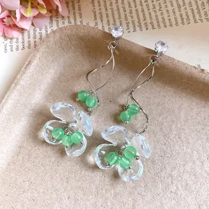 Détail de boucles d'oreilles fleur en résine muguet avec perles vertes et tiges