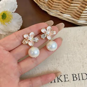Detail view of 18K gold plated camellia earrings with elegant pearls and zircons