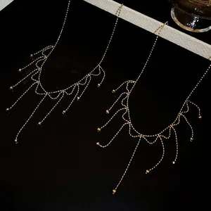 Detailed view of elegant gold-toned tassel necklaces on a dark reflective background