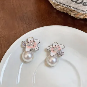 Elegant close-up of camellia flower stud earrings with white pearl drop and zircon