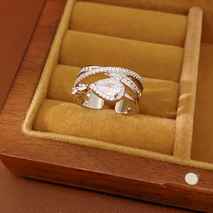 Detail of a multi-layer crisscross silver ring with a large pear-shaped zircon in a box.