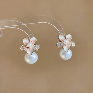 Close-up detail of 18K gold plated camellia earrings with pink enamel and pearls