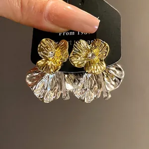 Eleganti orecchini a fiore in oro e argento con un centro di cristallo brillante.