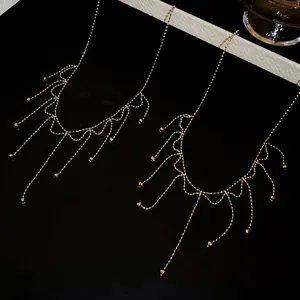 Close-up detail of a delicate gold tassel necklace with shimmering beads.