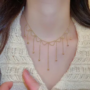 Detailed close-up showing elegant gold beaded fringe necklace worn by model in light