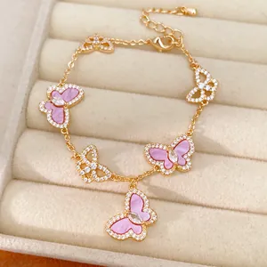 Exquisites Detail eines goldenen Schmetterlingsarmbands mit rosa Einlage und Zirkonia