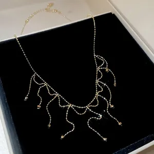 Detailed close-up of a gold tassel fringe necklace with delicate beads in a black gift box