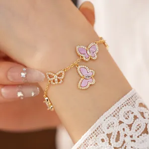 Detailaufnahme eines goldenen Schmetterlingsarmbands mit lila Inlays und Zirkonia