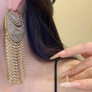 Close-up of elegant gold hoop earrings featuring long sparkling rhinestone tassels and crystals