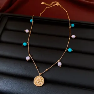 Detail of 18K gold necklace with turquoise and pearl beads on black jewelry display.