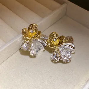 Primo piano dettagliato della trama metallica plissettata di questi orecchini a forma di fiore