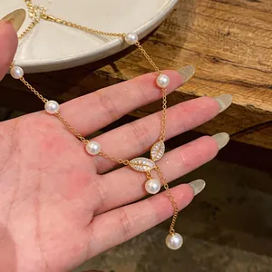 Gros plan d'un élégant collier en perles et feuilles de zircon plaqué or 18 carats
